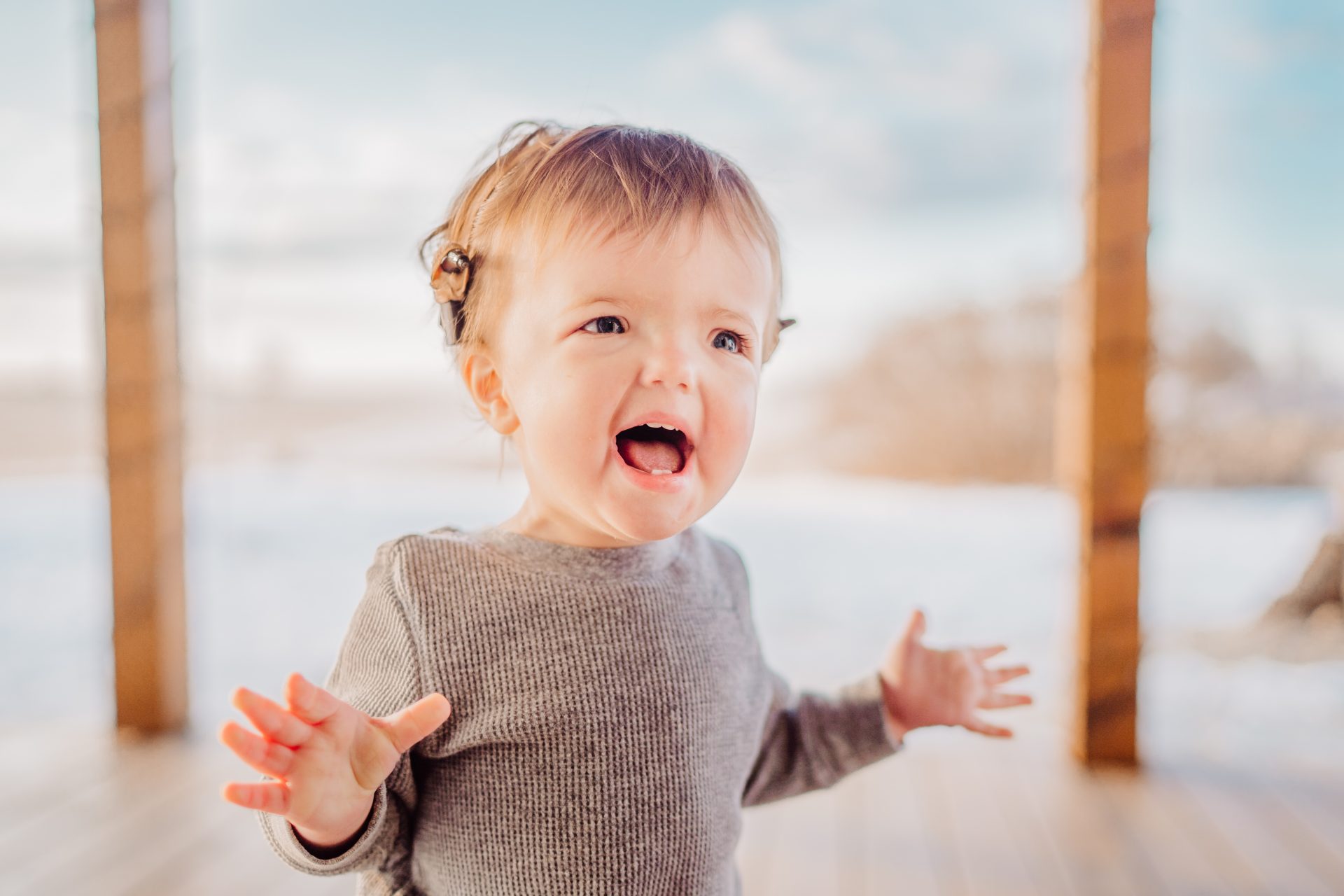 A joyful toddler with a bright smile and adorable pigtail hairstyle expressing excitement and wonder on a sunny day, embodying the spirited essence celebrated in children's books about disabilities.