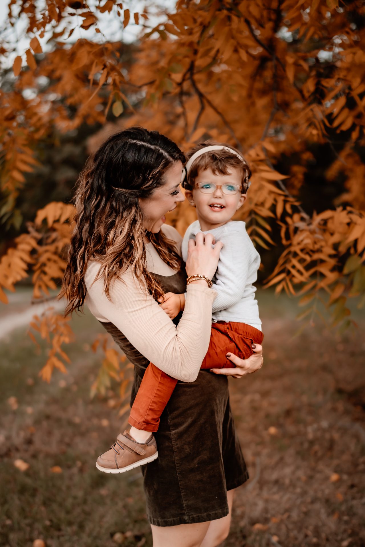 A joyful moment between mother and child, surrounded by the warm hues of autumn leaves, blossoms into a scene from a children's book about inclusion and raising a deaf child.
