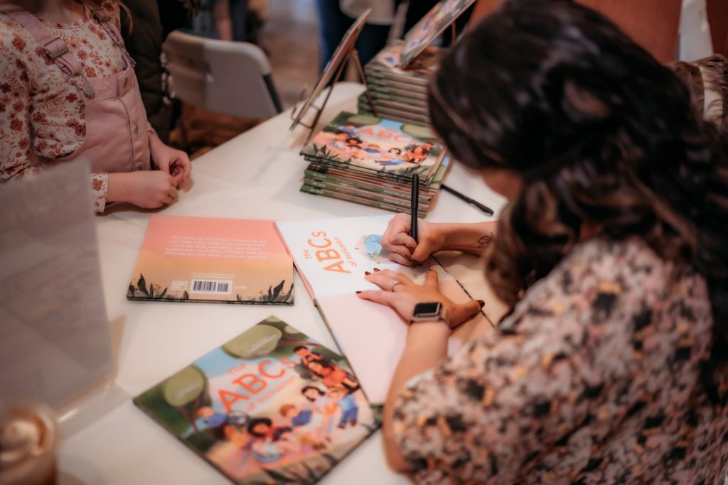 A person signing a copy of a children's book about disabilities titled 