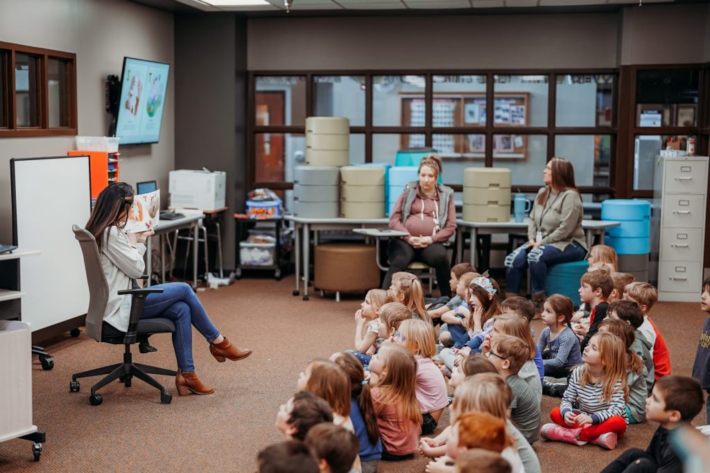 A storyteller reading a children's book about disabilities to an inclusive and attentive audience of children in a cozy library setting.