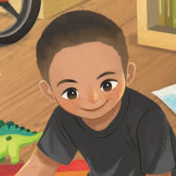 A smiling child with short dark hair and a dark shirt sits indoors on a wooden floor near a green toy dinosaur and some bookshelves.